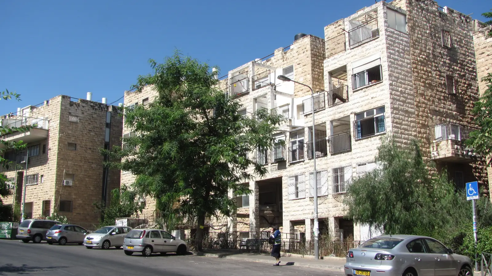 בנייני מגורים מאבן, עם תוספות בנייה ומרפסות, ברחוב בשכונת אונסדורף בירושלים